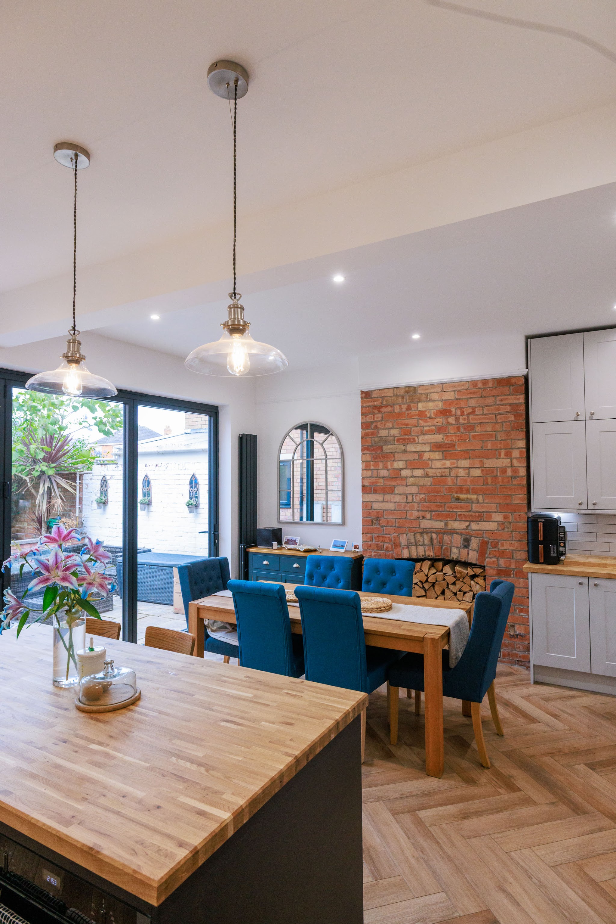 Waney-edge oak worktop island under copper pendant lights