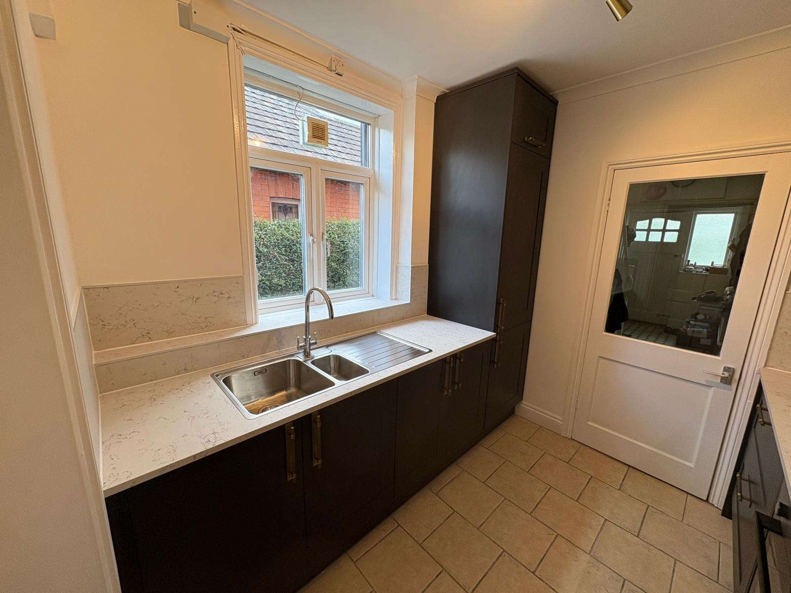Dark kitchen units with a white worktop and inset sink