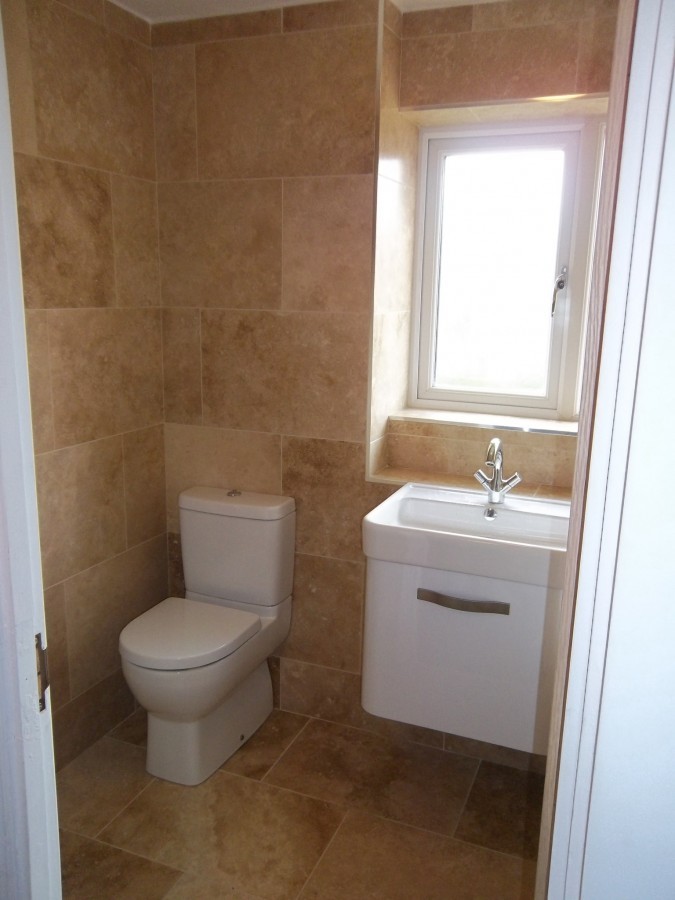 Travertine-tiled bathroom with a wall-hung basin