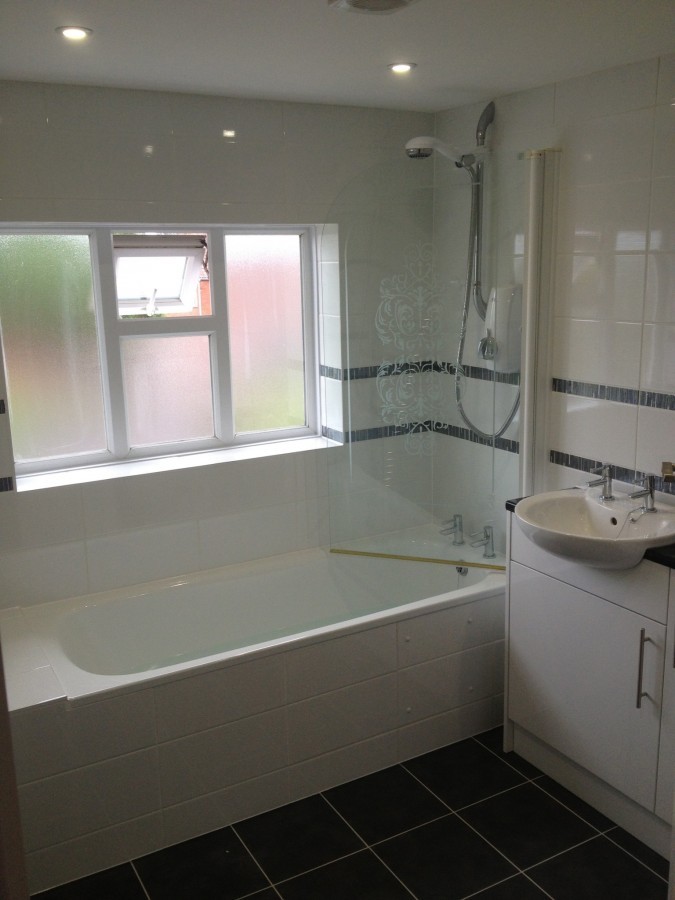 Bath with shower screen under a window