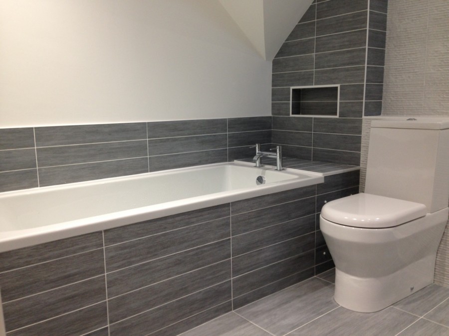 Bath and toilet with grey plank tiles and a recessed shelf