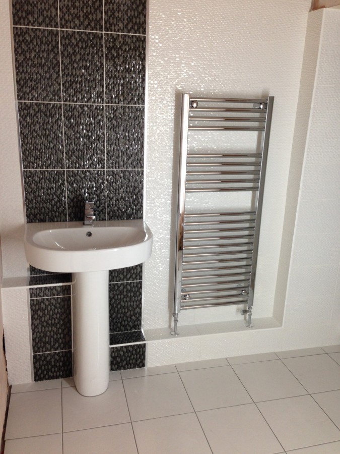 Mosaic feature wall with a pedestal basin and chrome rail