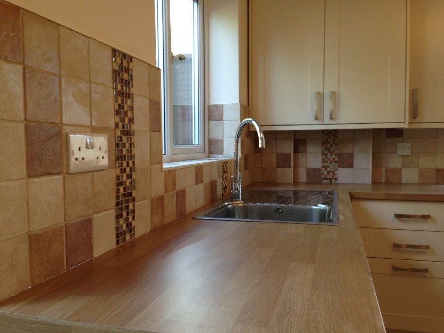 Tiled splashback with a mosaic strip above a timber worktop