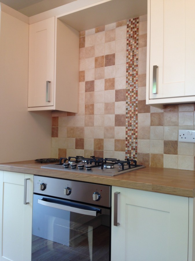 Cream units with a gas hob and tiled splashback