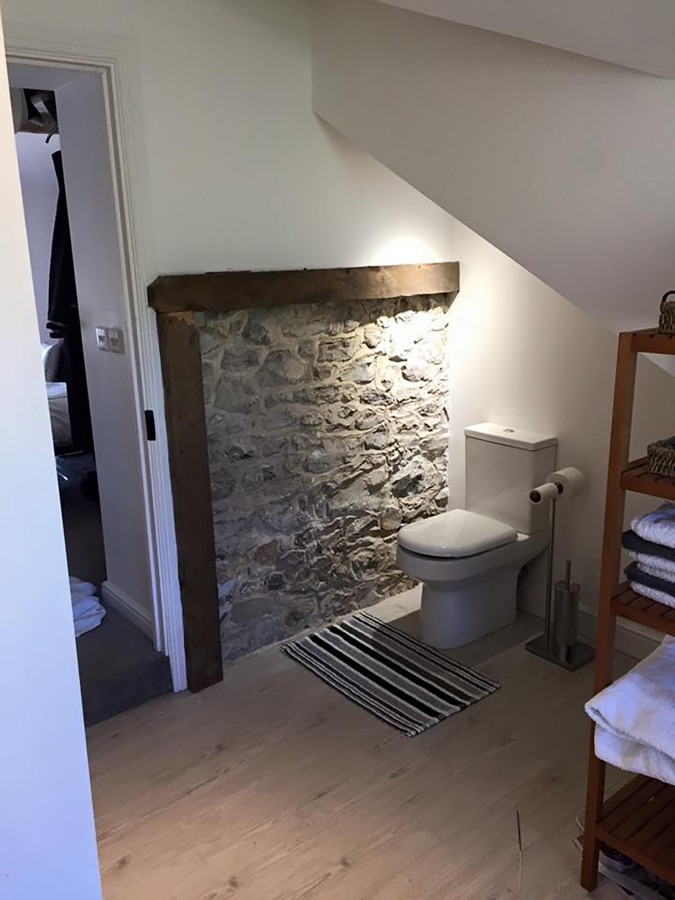 Cloakroom with an exposed stone wall and beam